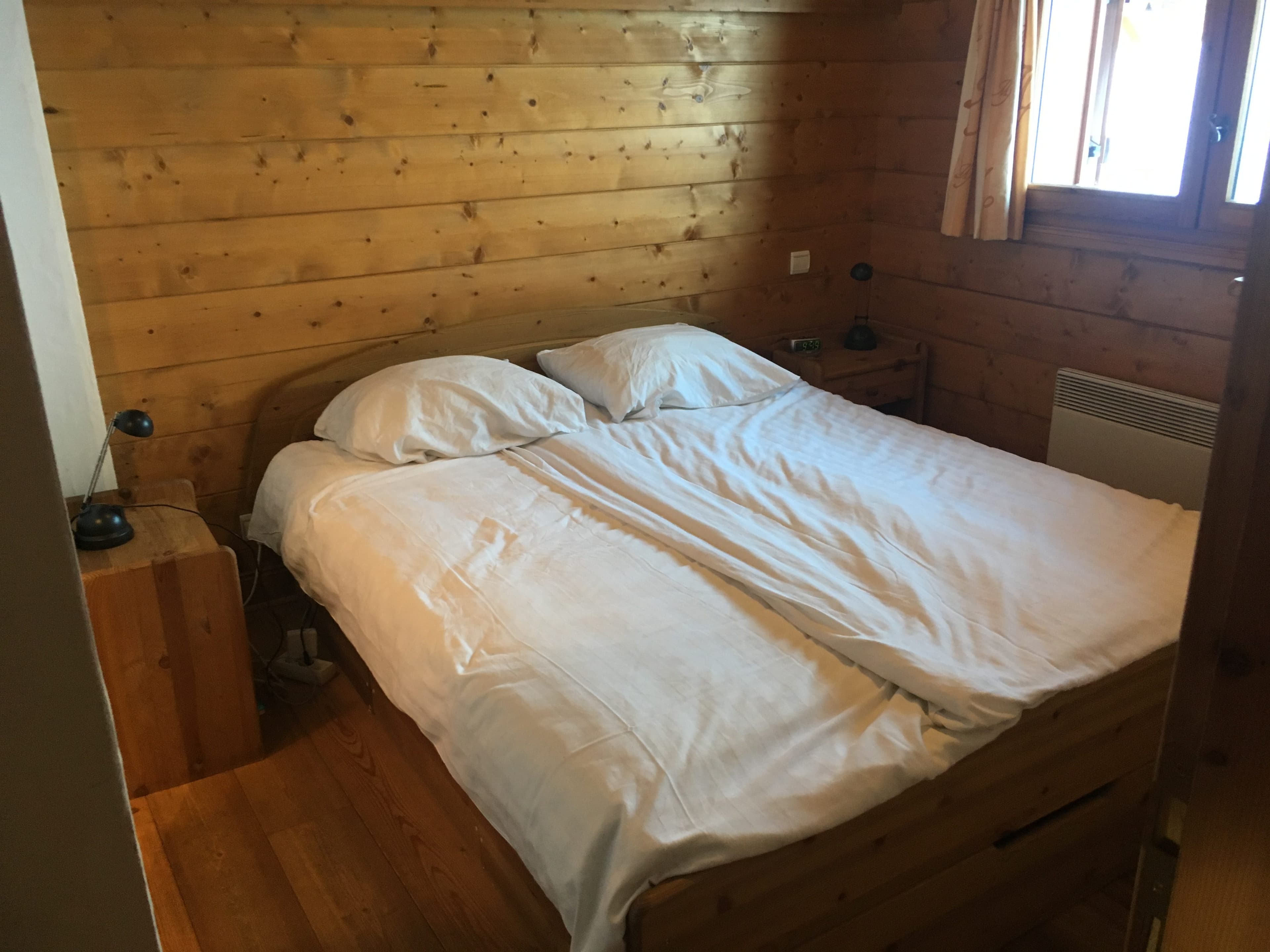 Slaapkamer met tweepersoonsbed en houten wanden